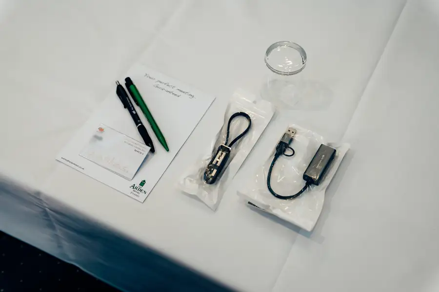 Delegate badge, branded pens and adapters laid out on a bench
